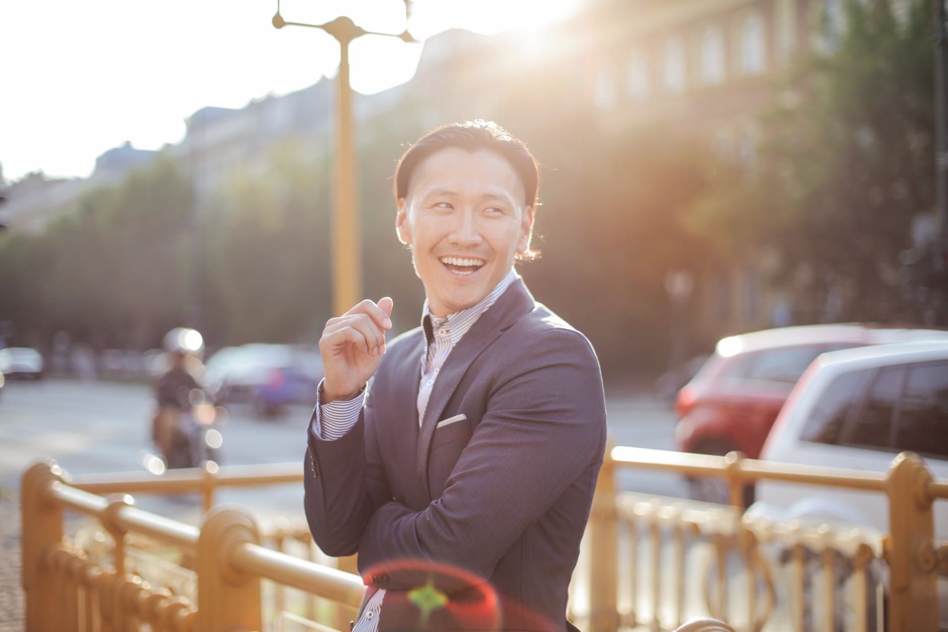 man in black suit leaning on railings smiling